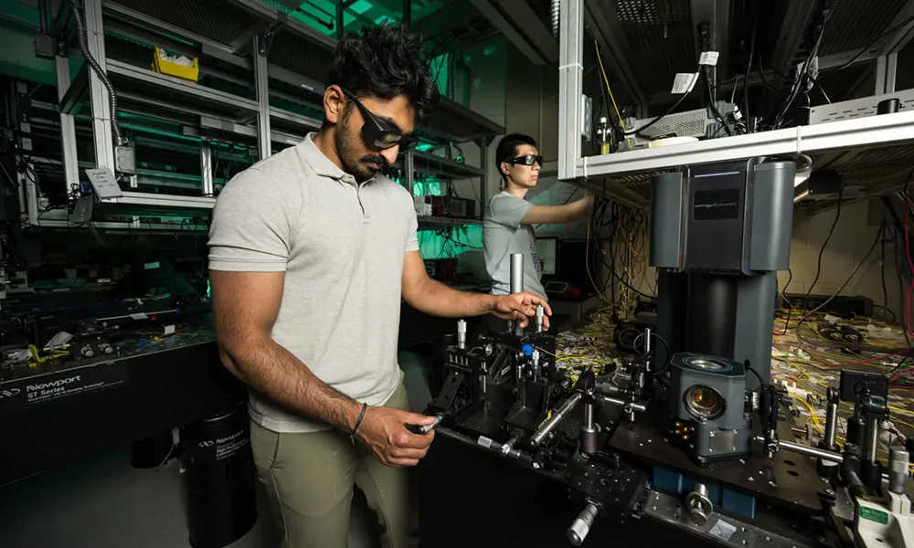 两名戴着防护眼镜的网赌论坛有哪些人员在光学实验室里操纵设备，以产生表面声波.